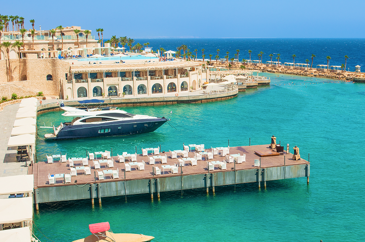 Luxuriöse Hotelanlage mit Steg, Liegen und Yacht an türkisfarbenem Meer in Ägypten.