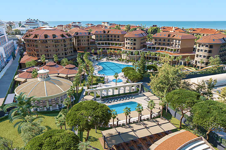 Großer Resortbereich mit Pool und Strand, umgeben von einem Hotel, ideal für Entspannung und Freizeitaktivitäten.
