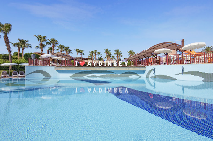 Luxuriöser Hotelpool mit schattenspendenden Sonnenschirmen und üppigen Palmen, perfekt für einen entspannten Tag.