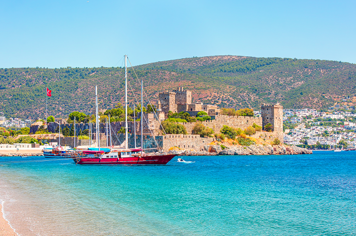 Am Strand von Bodrum steht ein Boot in der Nähe einer alten Burg.