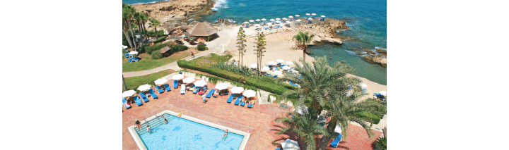 Luftaufnahme eines Resorts mit Pool und Strand, umgeben von üppigem Grün und klarem Wasser.