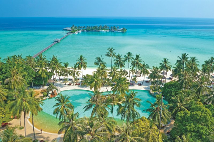 Blick auf eine tropische Insel mit Palmen, einem großen Pool und einem Steg, der ins Meer führt.