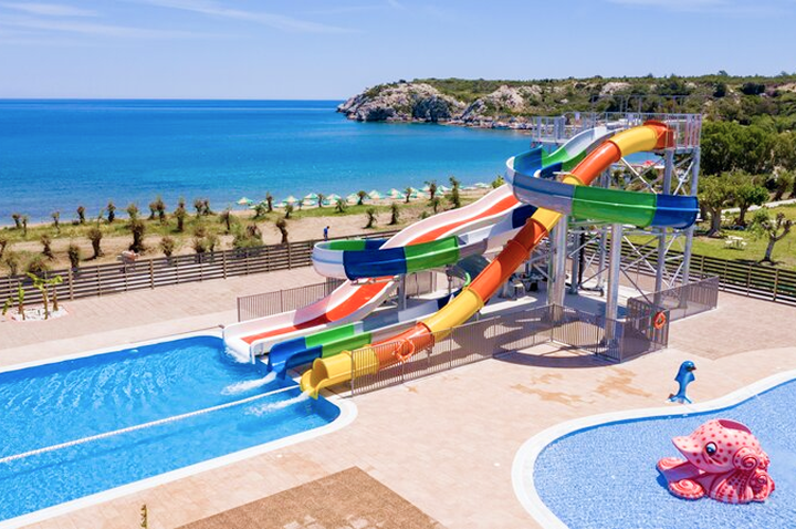 Wasserrutsche in einem Resort, umgeben von Strand und Ozean, ideal für einen aufregenden Tag am Wasser.